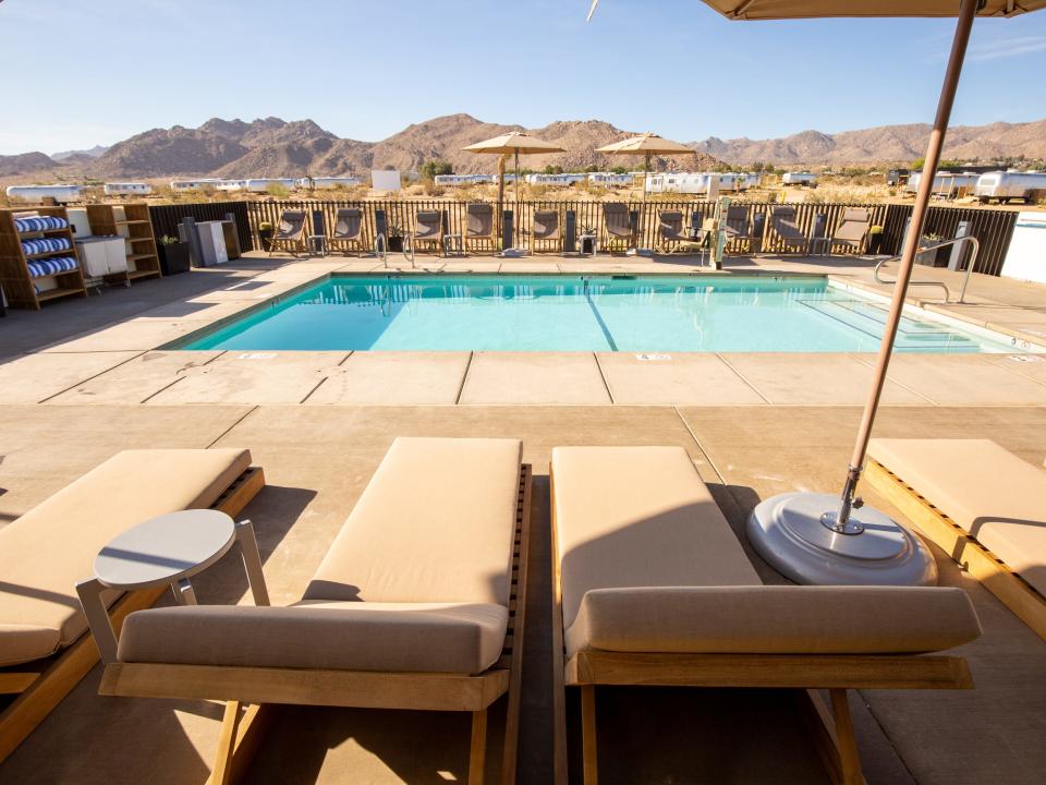 Lounge chairs by a pool overlooking desert hills.