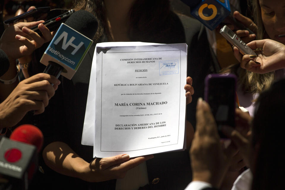 FILE - Venezuela's former opposition lawmaker Maria Corina Machado shows documents she delivered to the headquarters of the Organization of American States (OAS) where she reported that she is being excluded from the National Assembly, as she was stripped of her seat in Congress after accused of treason by the government of President Nicolas Maduro in Caracas, Venezuela, Friday, June 13, 2014. The government’s move to ban her from public office in 2023 has helped rally the fractured opposition and focus much-needed attention on their effort to hold an independent presidential primary election. (AP Photo/Ramon Espinosa, File)