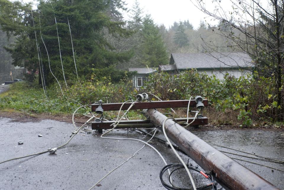 Utility pole and lines lie on the road north of Lincoln City, Ore., Monday Nov. 19, 2012 after being felled by trees knocked down by high winds.   A storm bearing down on the Pacific Northwest has taken the life of an elk hunter on the Oregon Coast and hit the region with mudslides, high winds and mountain snow.  (AP Photo/The Oregonian, Brent Wojahn)