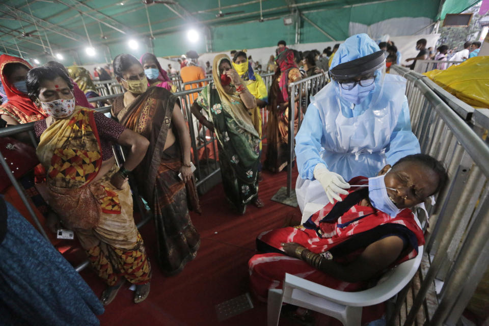 An Indian woman reacts as a health worker takes a nasal swab sample to test for COVID-19 at a facility erected at a railway station to screen people coming from outside the city, in Ahmedabad, India, Friday, Sept. 18, 2020. India's coronavirus cases jumped by another 96,424 in the past 24 hours, showing little sign of leveling. India is expected to have the highest number of confirmed cases within weeks, surpassing the United States, where more than 6.67 million people have been infected. (AP Photo/Ajit Solanki)