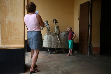Woman takes a picture of a boy posing with a metal sculpture at the Da-Silva Museum in Porto-Novo