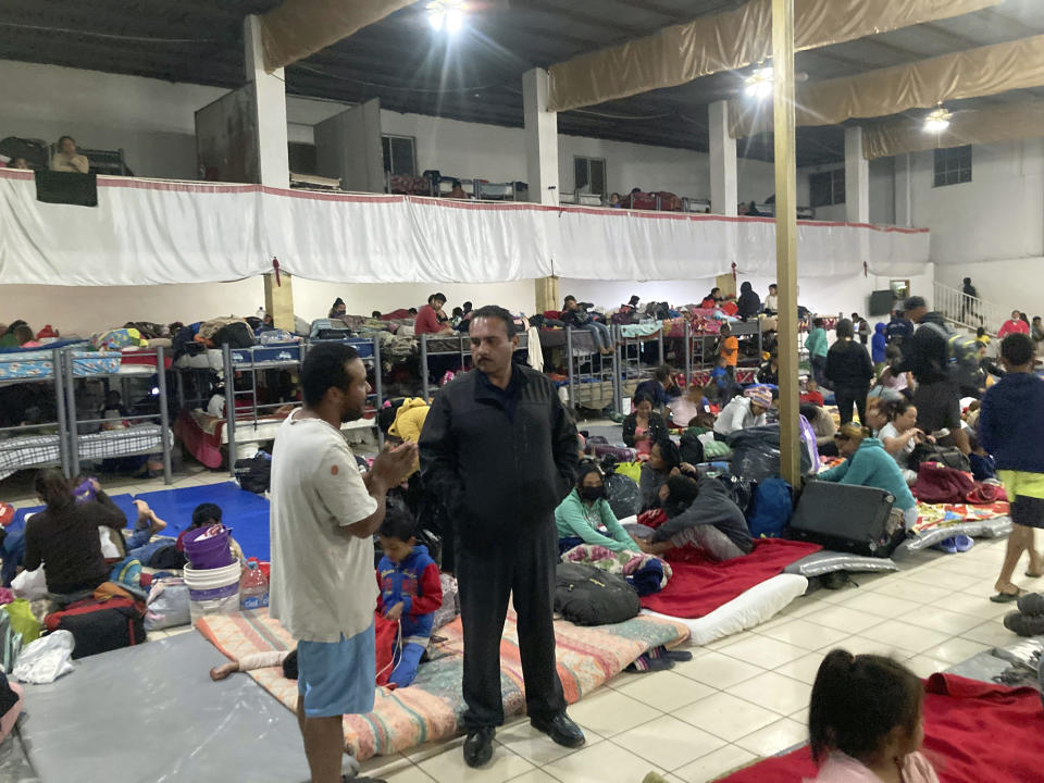 Gustavo Banda, center right, pastor of Templo Embajadores de Jesus, Tijuana's largest migrant shelter, speaks with migrants at a shelter, Thursday, Oct. 13, 2022, in Tijuana, Mexico. The Biden administration's policy shift on Venezuelan migrants may pose an enormous challenge to overstretched Mexican shelters. The U.S. has coupled plans to let up to 24,000 Venezuelans apply online to fly to the U.S. for temporary stays with a pledge to immediately turn back Venezuelans who cross the border illegally from Mexico. (AP Photo/Elliot Spagat)