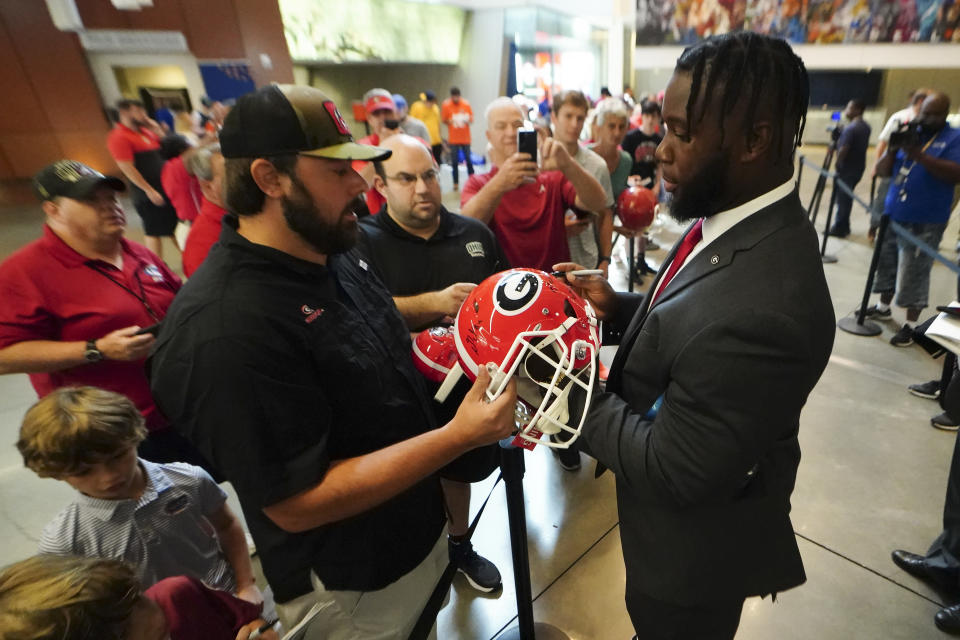 Georgia offensive lineman Sedrick Van Pran, right, signs autographs as he arrives for interviews during NCAA college football Southeastern Conference Media Days, Wednesday, July 20, 2022, in Atlanta. (AP Photo/John Bazemore)