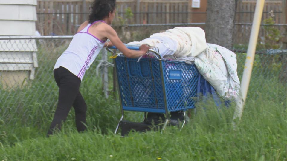 A woman pushes a cart after leaving the Water World Homelessness and Housing Help Hub.