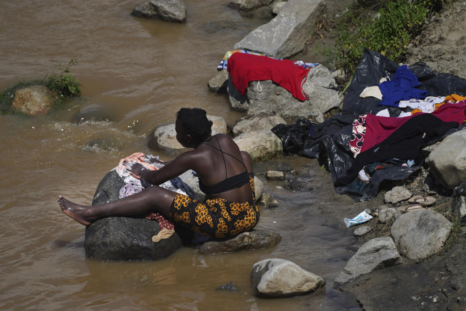 A woman who is part of a migrant caravan, washes her clothes on the banks of the in Huixtla River, Chiapas state, Mexico, Tuesday, Oct. 26, 2021, on a day of rest before continuing their trek across southern Mexico to the U.S. border. (AP Photo/Marco Ugarte)