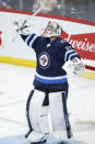 Winnipeg Jets goaltender Connor Hellebuyck (37) celebrates the team's win over the New Jersey Devils in an NHL hockey game Friday, Dec. 3, 2021, in Winnipeg, Manitoba. (John Woods/The Canadian Press via AP)