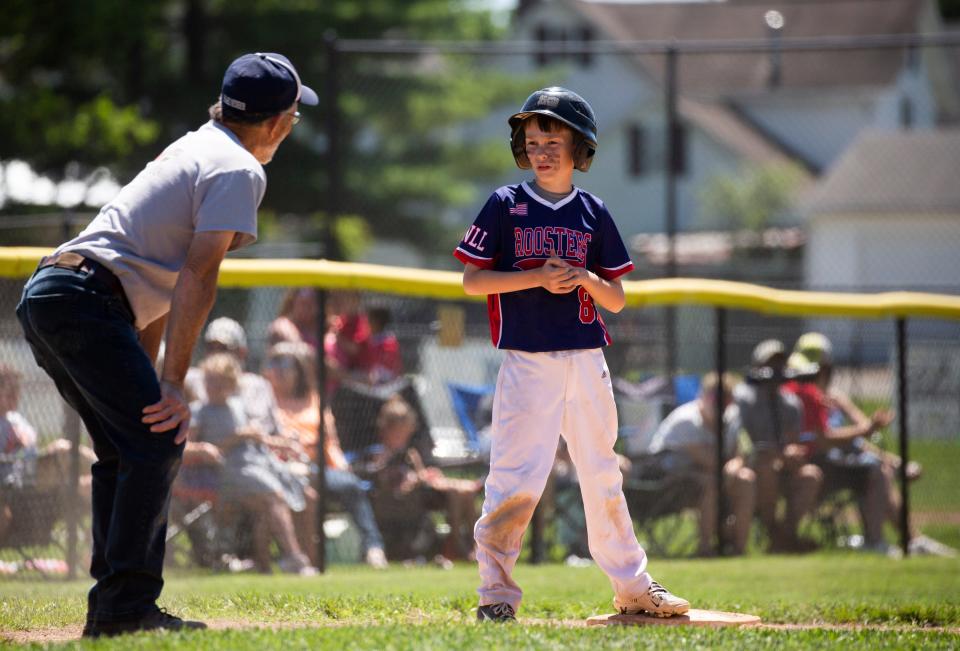 Rooster's base runner Nixon Gartner talks to an umpire during their Farm Division game against Texas Road House on Saturday in the Shrine Tournament quarterfinals.