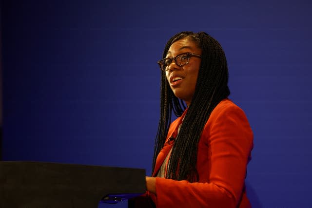 Kemi Badenoch at lectern in orange jacket