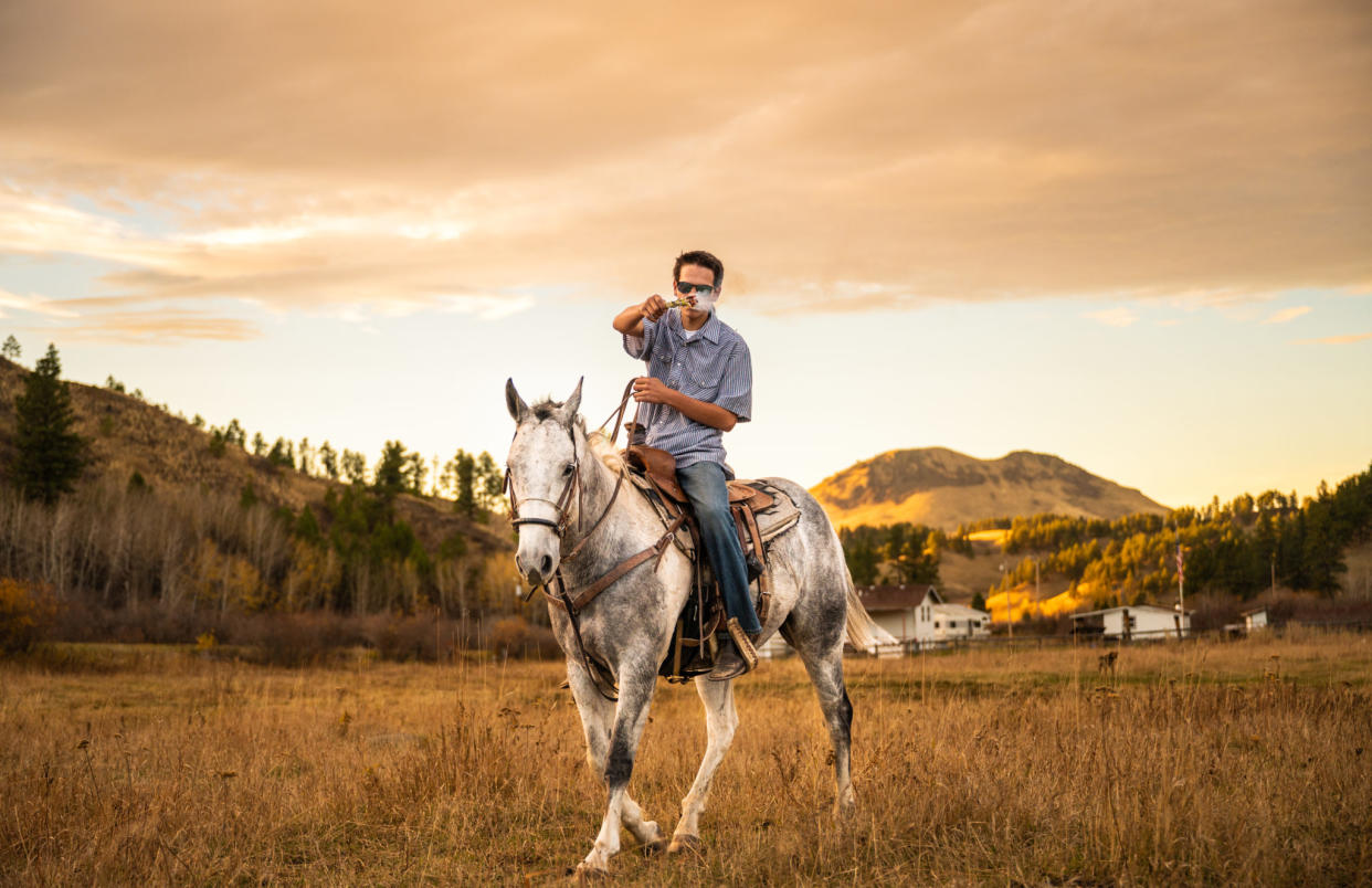 Bridger Morsette, 15, rides his horse, Bud Light, through the Rocky Boy’s Reservation while he burns a bundle of smoldering sage as a part of the Smudge the Rez event on Oct. 18, 2023. (Photo/Ava Rosvold))