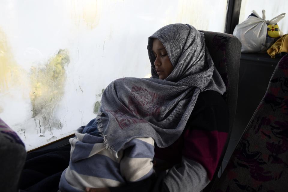 A woman holds a child as they sleep inside a bus at the toll stations of Malgara, near the Greek port city of Thessaloniki, on Wednesday, Oct. 23, 2019. Protesting local residents in northern Greece set up roadblocks to try and prevent migrants from settling in the area. The government has promised to expand a network of refugee camps and hotel residence programs on the Greek mainland in an effort to ease severe overcrowding at facilities on islands near the Turkish coast. (AP Photo/Giannis Papanikos)