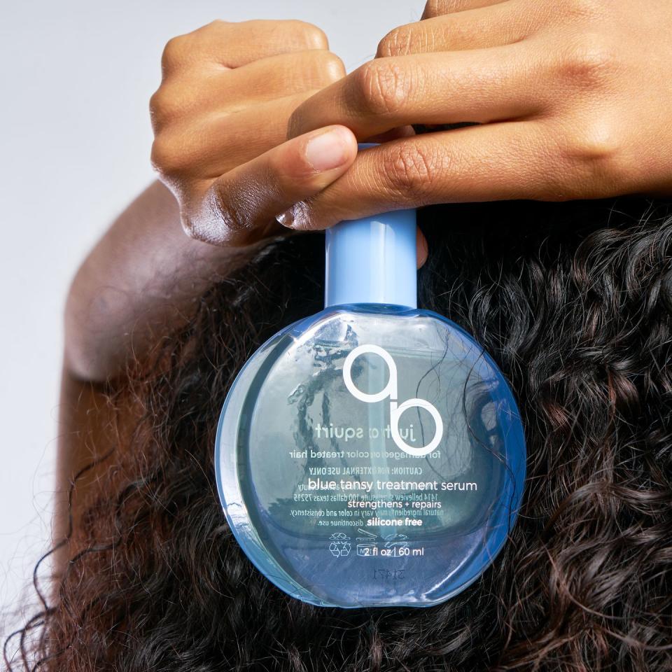 a person holding a bottle of blue tansy treatment serum