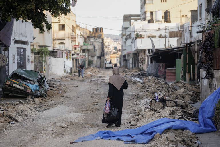 Una mujer palestina camina por una calle dañada en el campo de refugiados de Yenín, en Cisjordania, el miércoles 5 de julio de 2023, después de que Israel retirase sus fuerzas del bastión miliciano, lo que puso fin a una intensa operación de dos días que mató al menos a 13 palestinos, expulsó a miles de personas de sus casas y dejó un rastro de destrucción a su paso. También murió un soldado israelí. (AP Foto/Majdi Mohammed)