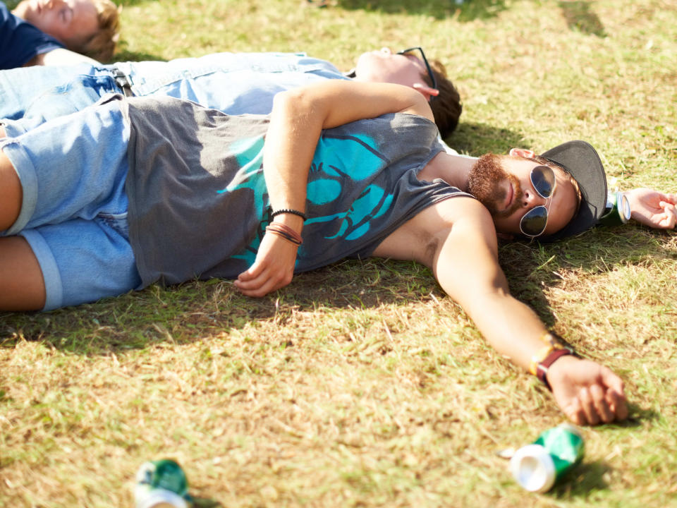 A few guys passed out on the grass after consuming too much alcohol or drugs at a festival. (Photo via Getty Images)