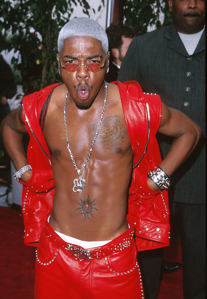 Sisqo with his hands on his shoulders and making an O with his mouth