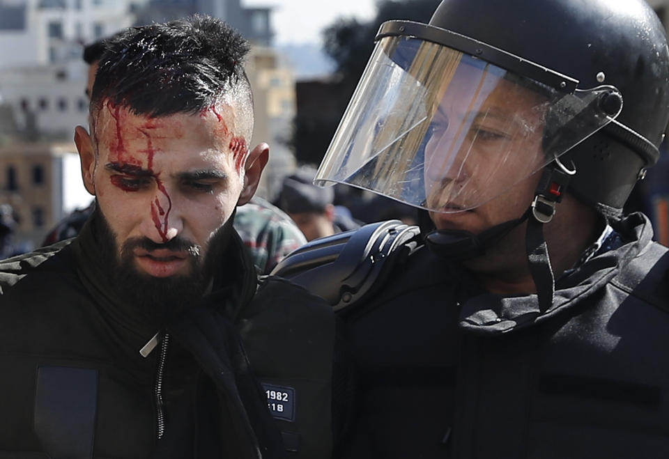 Riot police arrest an injured anti-government protester attempting to prevent the Lebanese lawmakers from reaching the parliament building to attend the 2020 budget discussion session, in downtown Beirut, Lebanon, Monday, Jan. 27, 2020. Lebanese security forces scuffled with protesters near the parliament building, where lawmakers are scheduled to begin a two-day discussion and later approval of the budget amid a crippling financial crisis. (AP Photo/Hussein Malla)