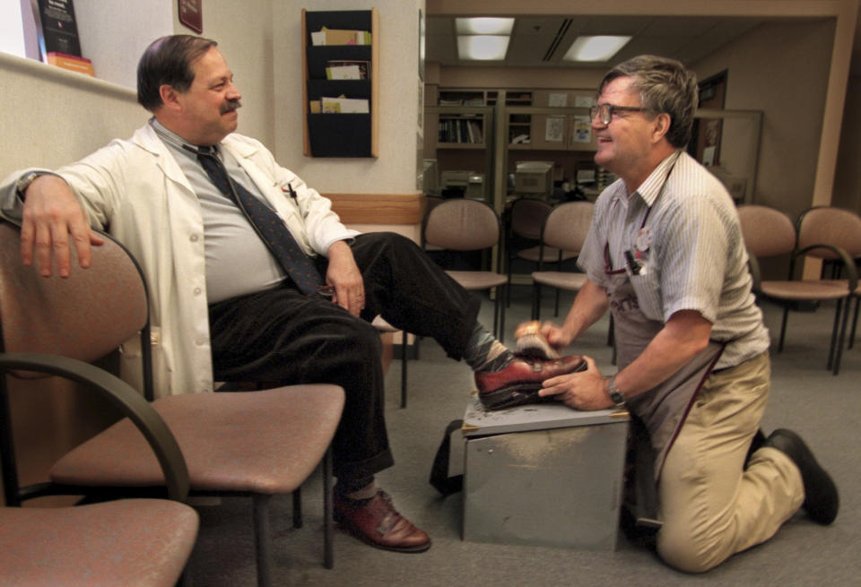 In this November 1998 photo, Dr. Samuel Kocoshis, director of Gastroenterology at Children's Hospital of Pittsburgh, gets a shoe shine from Albert Lexie of Monessen. Lexie, who died Tuesday, Oct. 16, 2018, donated more than $200,000 in tips to a Pittsburgh children’s hospital. (Bill Wade/Pittsburgh Post-Gazette via AP)