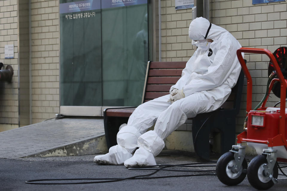 A member of the medical team takes a rest outside a hospital in Daegu, South Korea, Sunday, Feb. 23, 2020. South Korea's president has put his country on its highest alert for infectious diseases, saying Sunday that officials should take "unprecedented, powerful" steps to fight a viral outbreak. (Im Hwa-young/Yonhap via AP)