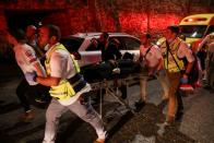 Rescue workers carry injured people outside a synagogue in Givat Zeev