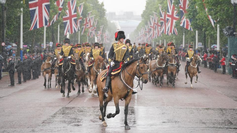 Horses ride down the Mall in heavy rain