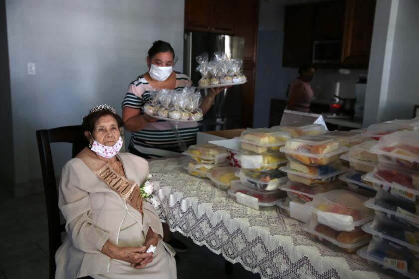 LOS ANGELES, CA - OCTOBER 03: Angelita Arellano waits for the start of her 98th birthday party as Angelica Gurrola brings food to pass out to the guests outside in East Los Angeles on Saturday, Oct. 3, 2020 in Los Angeles, CA. Angelita has 8 children, 36 great-grandchildren and family and friends came from near and far to celebrate. (Dania Maxwell / Los Angeles Times)