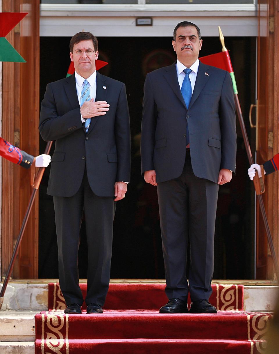 Iraqi Defense Minister Najah al-Shammari, right, and U.S. Defense Secretary Mark Esper, left, stand for their country's national anthems during a welcome ceremony at the Ministry of Defense, Baghdad, Iraq, Wednesday, Oct. 23, 2019. Esper has arrived in Baghdad on a visit aimed at working out details about the future of American troops that are withdrawing from Syria to neighboring Iraq. (AP Photo/Hadi Mizban)