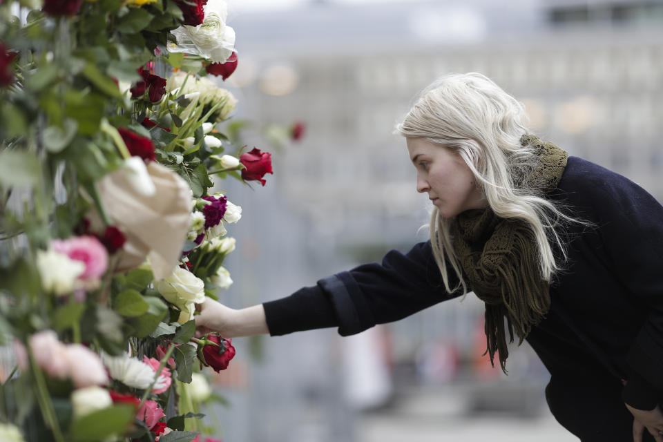 A woman places a flower on a fence following a suspected terror attack in central Stockholm, Sweden, Saturday, April 8, 2017. Swedish prosecutor Hans Ihrman said a person has been formally identified as a suspect "of terrorist offences by murder" after a hijacked truck was driven into a crowd of pedestrians and crashed into a department store on Friday. (AP Photo/Markus Schreiber)
