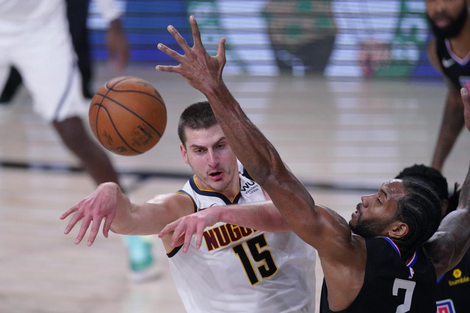 Denver Nuggets center Nikola Jokic (15) passes to ball past Los Angeles Clippers forward Kawhi Leonard (2) during the first half of an NBA conference semifinal playoff basketball game Tuesday, Sept. 15, 2020, in Lake Buena Vista, Fla. (AP Photo/Mark J. Terrill)