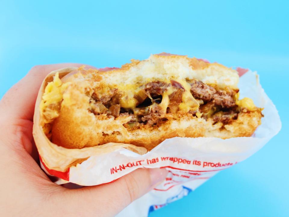 bitten into in n out double double on blue background