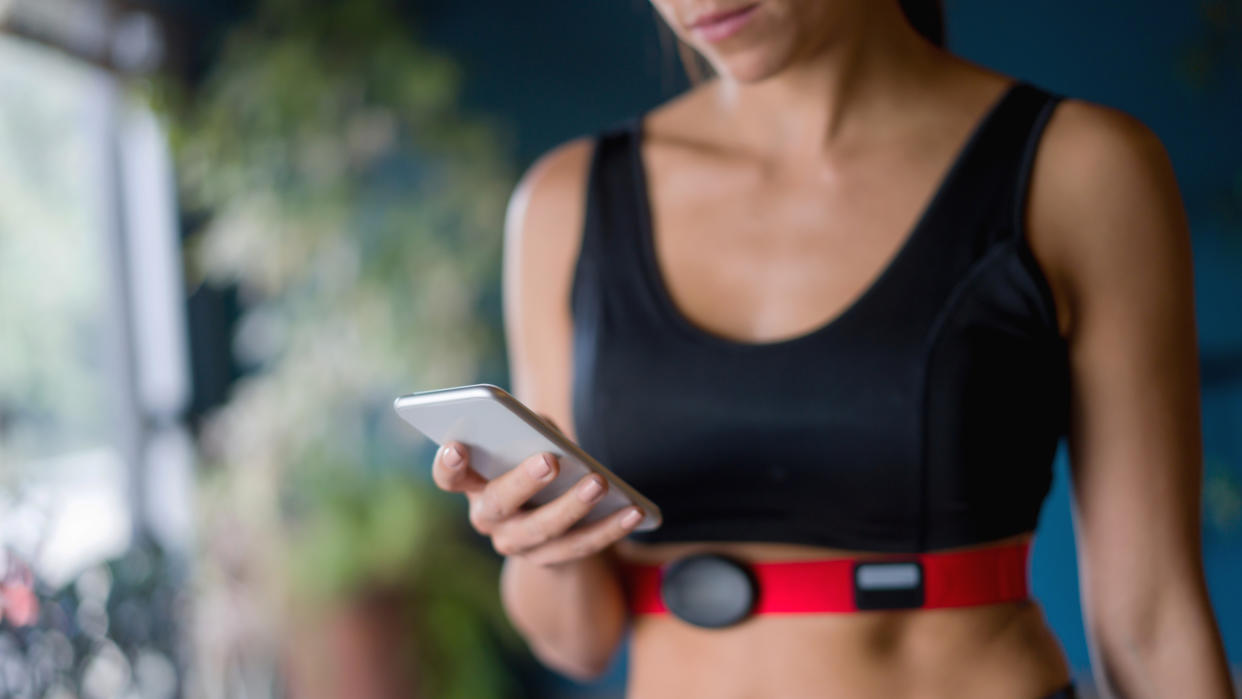  Woman using phone wearing chest strap heart rate monitor 