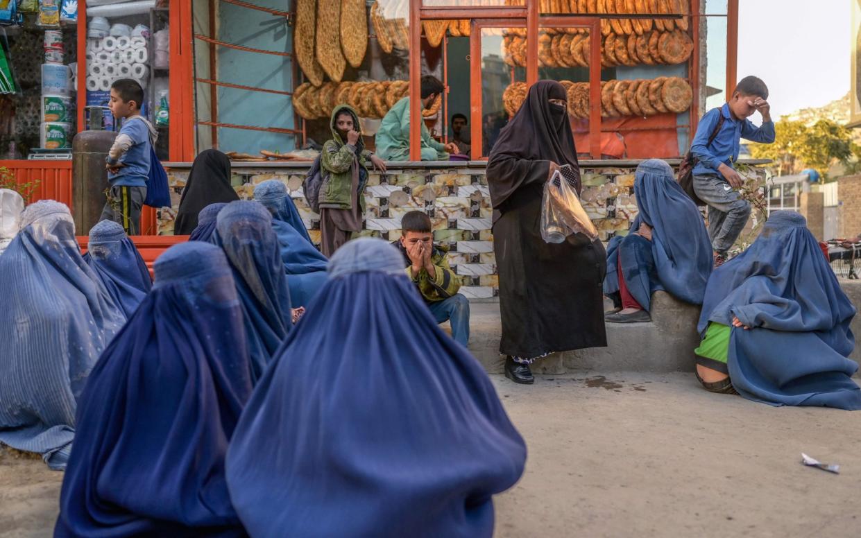 TOPSHOT - In this photograph taken on October 20, 2021, burqa-clad women wait in front of a bakery to get bread donations in Kabul. (Photo by BULENT KILIC / AFP) - BULENT KILIC / AFP