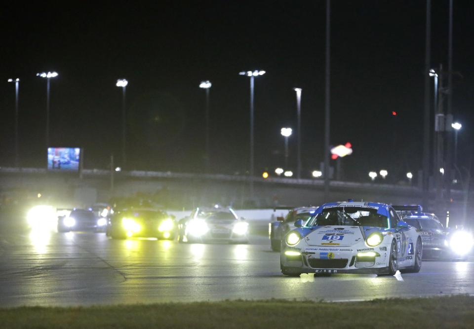 Jim Michaelian, front right, drives the Muehiner Motorsports Porsche 911 GT in the horseshoe turn followed by a group of cars during the IMSA Series Rolex 24 hour auto race at Daytona International Speedway in Daytona Beach, Fla., Saturday, Jan. 25, 2014. (AP Photo/John Raoux)