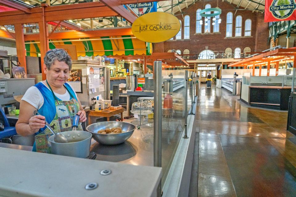 Lily Stockton stirs a mixture to add to ingredients for no-bake cookies at Just Cookies, Tuesday, Aug. 29, 2023 in City Market. Stockton has run the business with her husband, David Stockton, for 35 years. They are concerned about the state of the market, especially the fact they are on month-to-month lease. City Market is half empty, and vendors are worried about the future. Many of the empty booths can be seen here, at right.