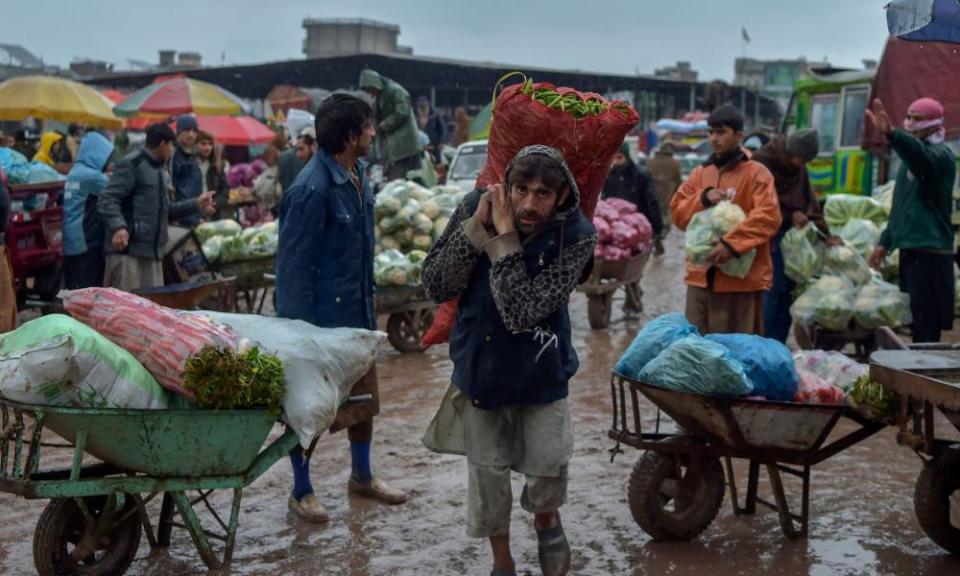 Traders and labourers work during a rainy day at a vegetable market in Peshawar