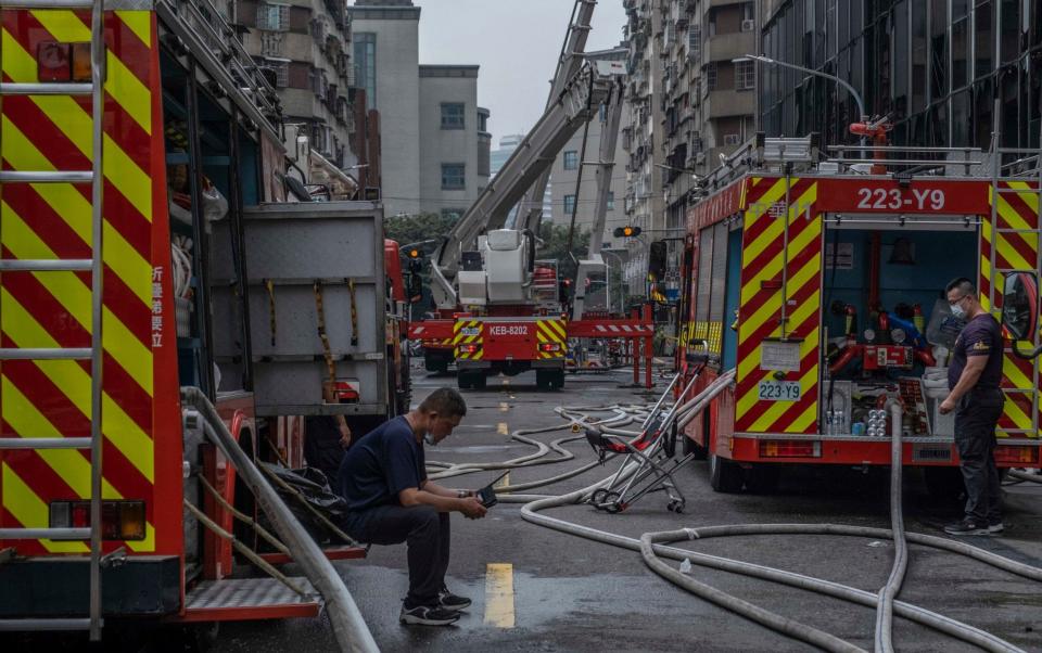 Firefighters take a break after fighting a fire at a residential building - Getty Images AsiaPac 