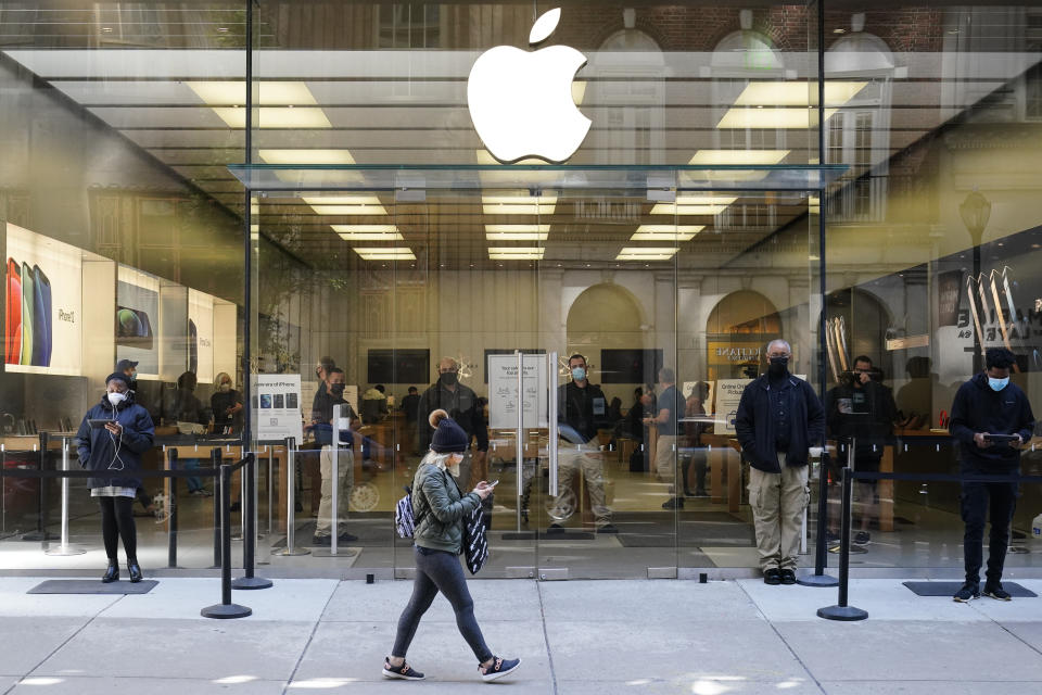 A person looks at her phone as she walks by the Apple store in Philadelphia, Monday, April 26, 2021. (AP Photo/Matt Rourke)