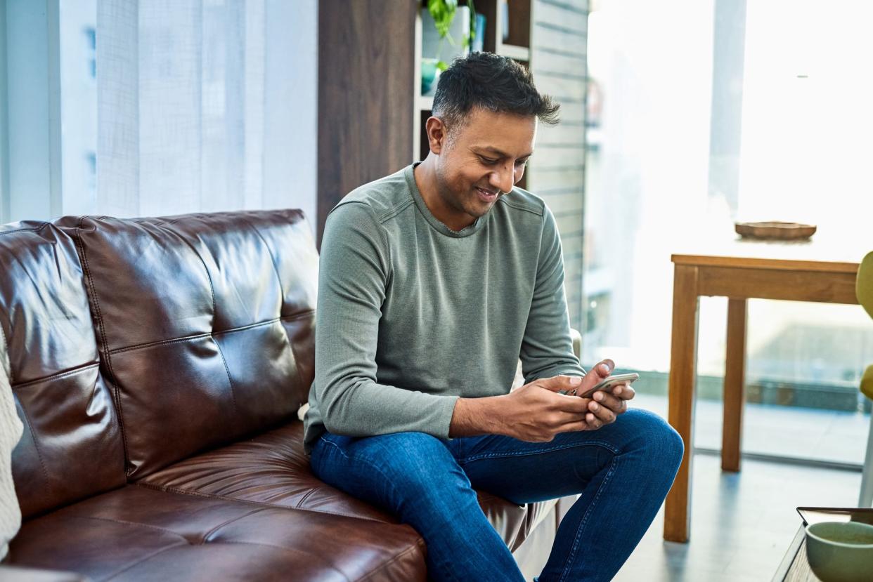Shot of a man using a smartphone on the sofa at home