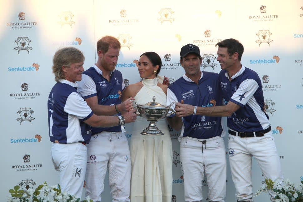 Meghan Markle hands Prince Harry a trophy after his team won a charity polo match