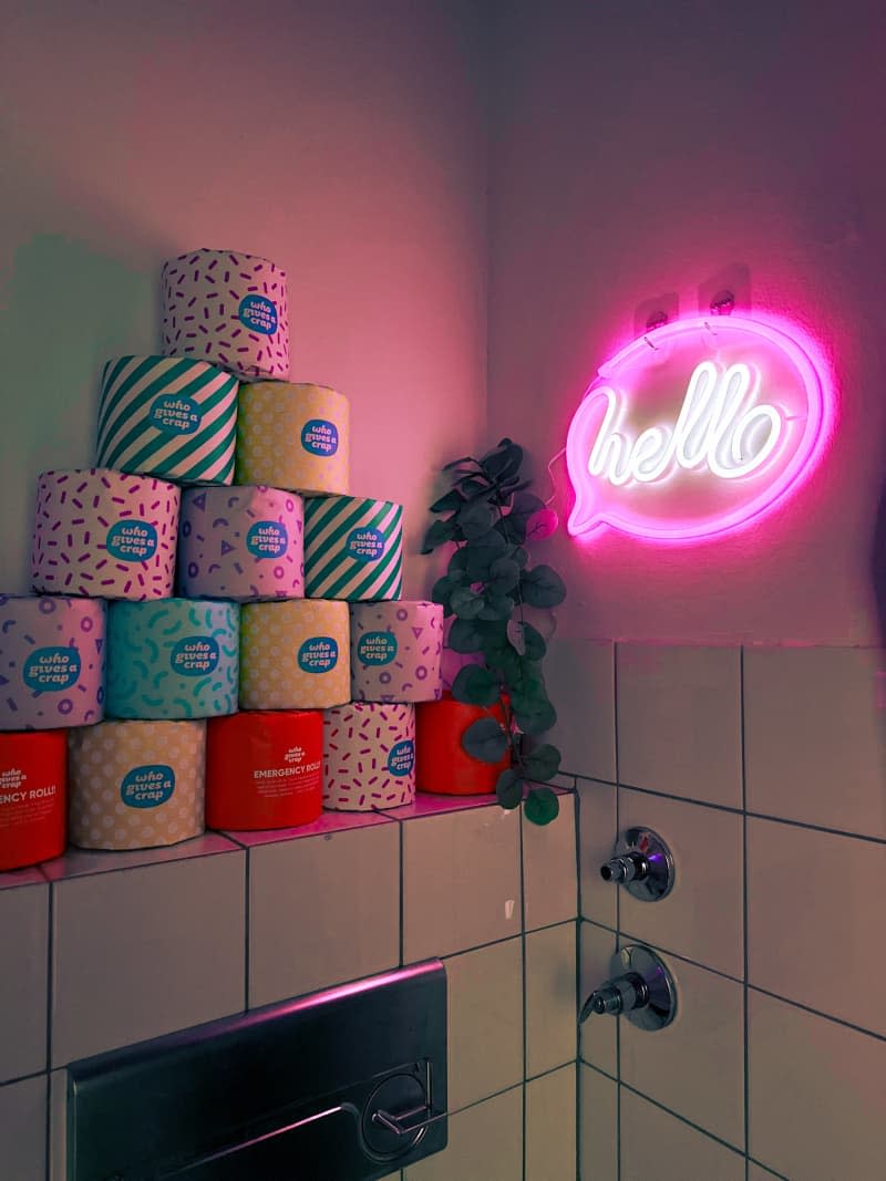 stack of colorful paper covered toilet paper, neon hello sign