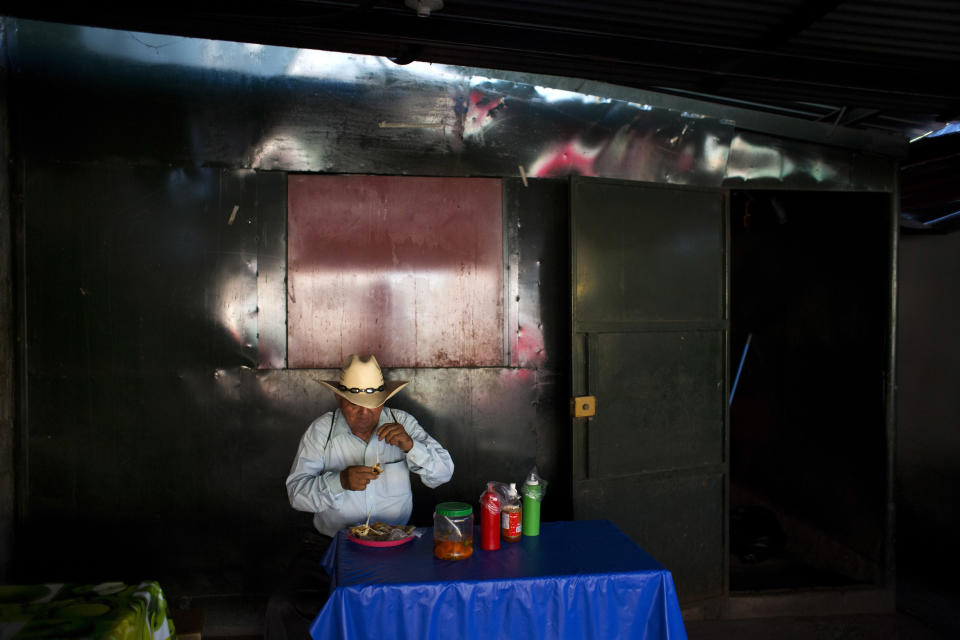 In this Aug. 18, 2018 photo, Gregorio Marquez Chica eats lunch inside the market in Intipuca, El Salvador. Nationwide, Salvadorans receive $4 billion a year in U.S. remittances, about 15 percent of their GDP. In El Salvador, a laborer might earn $5 a day, while in Washington D.C., the minimum wage is $11.50 per hour. (AP Photo/Rebecca Blackwell)