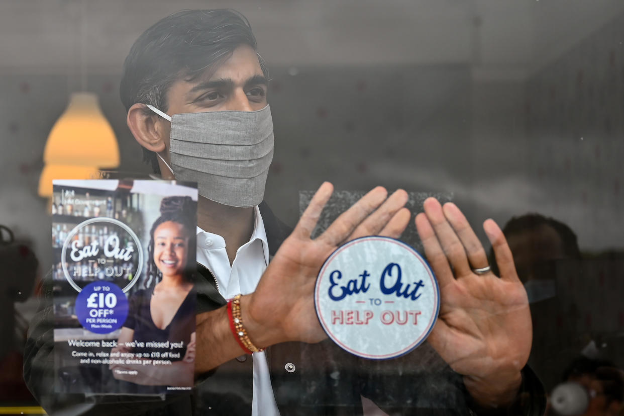 Chancellor of the Exchequer Rishi Sunak places an Eat Out to Help Out sticker in the window of a business during a visit to Rothesay on the Isle of Bute, Scotland. (Photo by Jeff J Mitchell/PA Images via Getty Images)