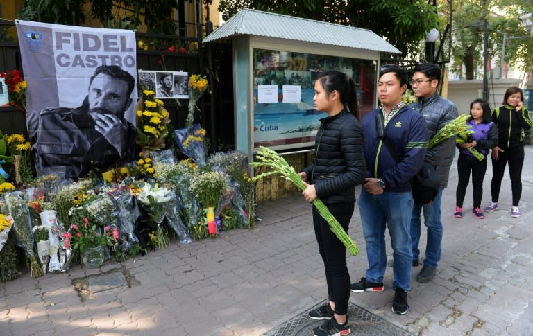 People hold flowers as they wait to pay tribute to the Cuban leader Fidel Castro at the Cuban embassy in Hanoi on December 4, 2016