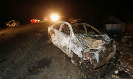 Motorists drive past the wreckage of cars burnt after a fireball from an tanker engulfed several vehicles and killed at least 25 people, near the Rift Valley town of Naivasha, west of Kenya's capital Nairobi, December 11, 2016. REUTERS/Thomas Mukoya