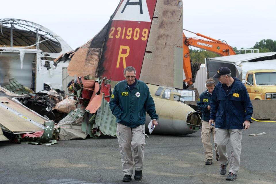 In this photo released via Twitter by the National Transportation Safety Board, NTSB investigator-in-charge Bob Gretz, left, walks Thursday, Oct. 3, 2019, with NTSB colleagues at the scene of a World War II-era bomber plane that crashed Wednesday at Bradley International Airport in Windsor Locks, Conn. (National Transportation Safety Board via AP)