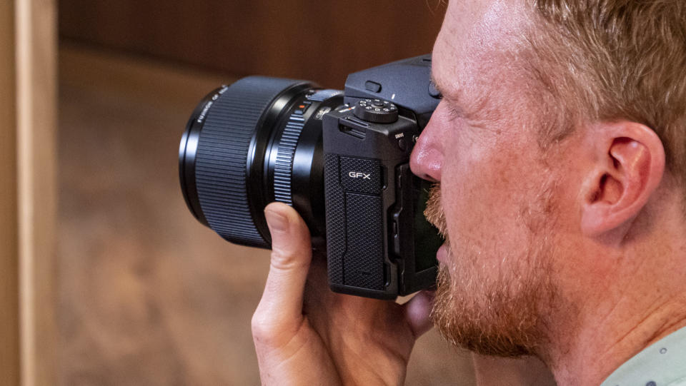 User holding the Fujifilm GFX100 II's viewfinder up to their eye