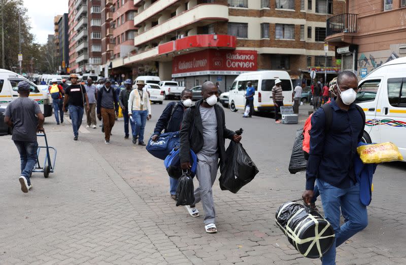 Passengers wearing masks walk to a taxi rank as residents of a number of African cities where the coronavirus is spreading are heading to the countryside to try to escape from the disease, in Johannesburg