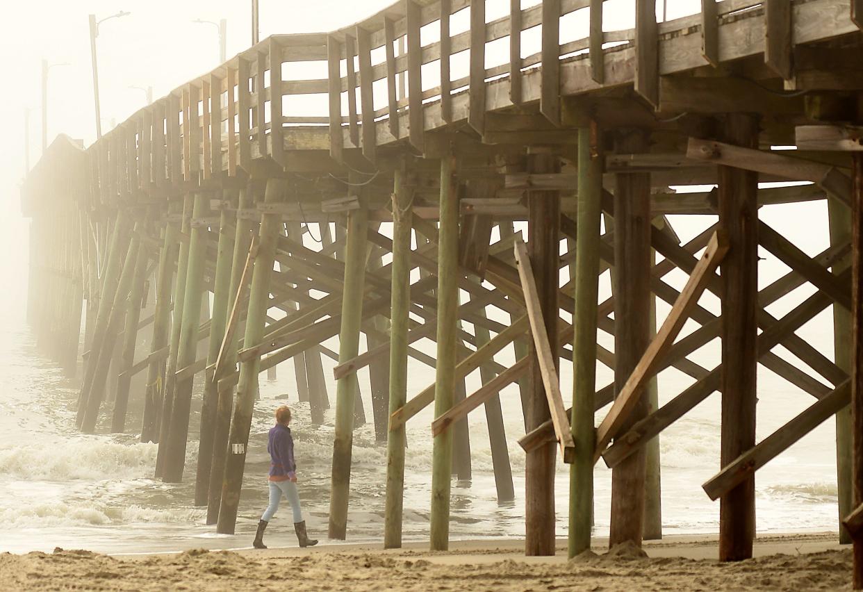 People walk along a foggy shoreline near the Holden Beach Pier Thursday, February 24, 2022, in Holden Beach. The town's proposed budget estimates the cost to repair the pier at $2.1 million.