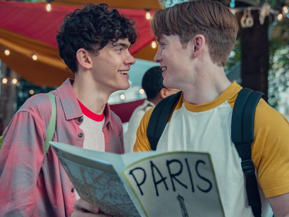 charlie and nick in heartstopper, looking lovingly into each others' eyes and hodling a map to paris