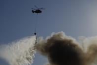 A Russian Emergency Situations Ministry helicopter dumps water on fire at a warehouse in Moscow, Russia, Saturday, June 19, 2021. A large fire broke out at a fireworks depot in the center of Moscow. The fire is raging at the area of 500 square meters, Russia emergency services said in the statement. (AP Photo/Pavel Golovkin)