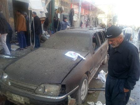 People gather at the site of bomb attacks in the town of Tuz Khurmato, 170 km (100 miles) north of the capital Baghdad, November 24, 2013. REUTERS/Stringer