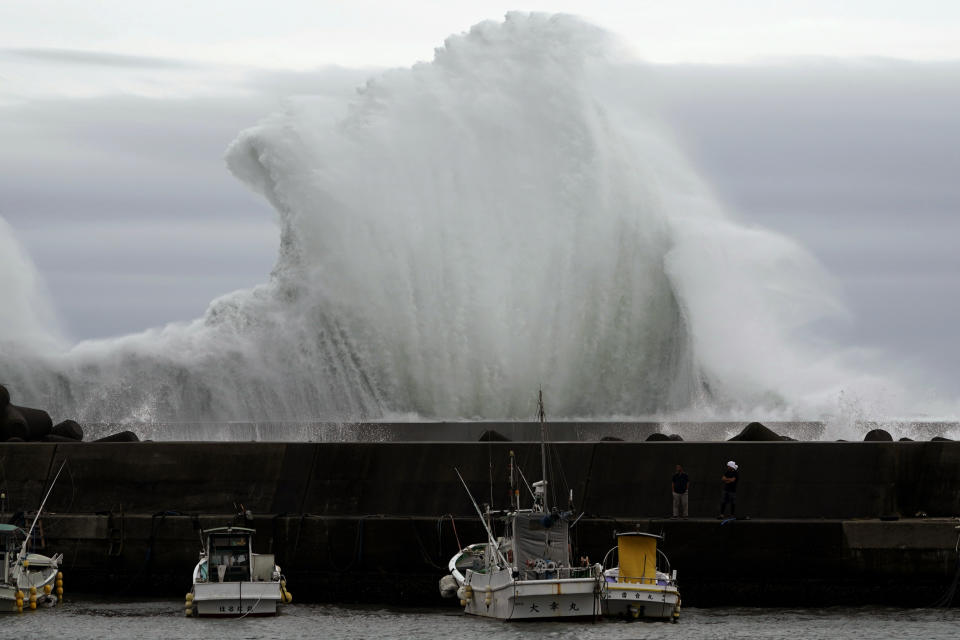 Men look at fishing boats as surging waves hit against the breakwater while Typhoon Hagibis approaches at a port in town of Kiho, Mie Prefecture, Japan Oct. 11, 2019. A powerful typhoon is advancing toward the Tokyo area, where torrential rains are expected this weekend. (Photo: Toru Hanai/AP)